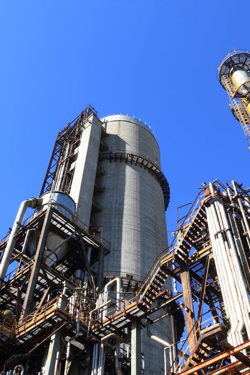 A towering industrial plant under a vivid blue sky, showcasing its intricate architecture and industrial prowess.